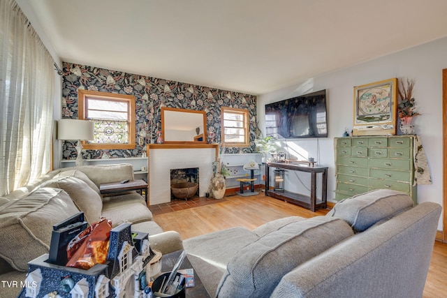 living area featuring a healthy amount of sunlight, a fireplace, baseboards, and wood finished floors