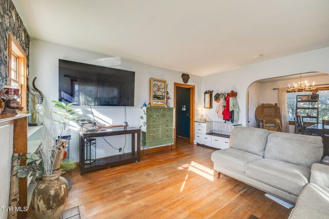 living room featuring arched walkways, wood finished floors, and an inviting chandelier