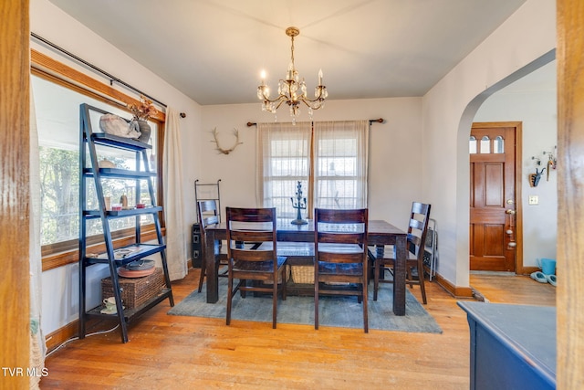 dining space with arched walkways, plenty of natural light, and light wood finished floors