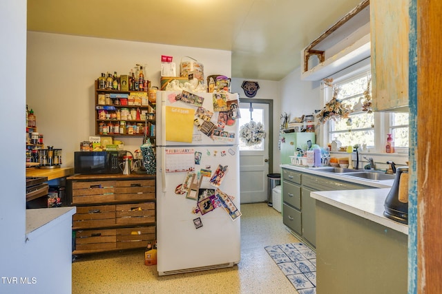 kitchen featuring black microwave, a sink, freestanding refrigerator, and a healthy amount of sunlight