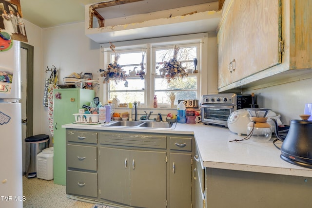 kitchen featuring light countertops, a sink, and gray cabinetry