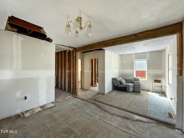 spare room featuring an inviting chandelier, a textured ceiling, visible vents, and beam ceiling