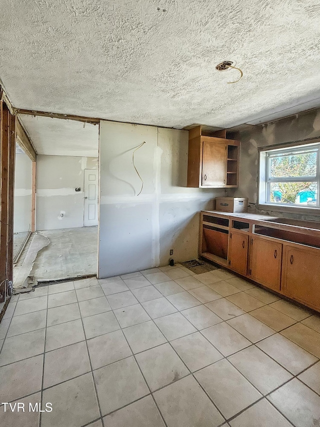 kitchen with brown cabinets, light tile patterned floors, open shelves, and a textured ceiling