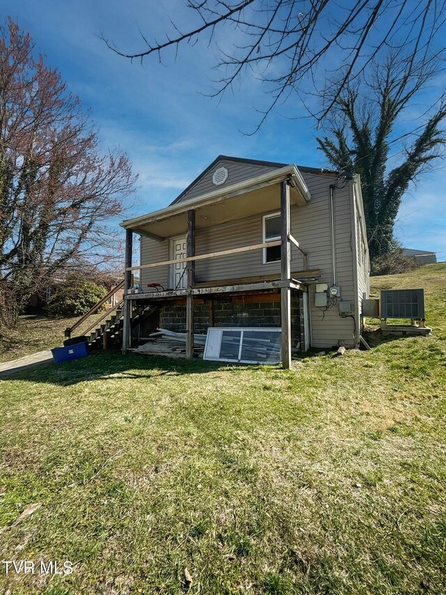 back of house featuring central AC unit and a lawn