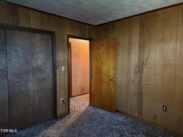 unfurnished bedroom with wood walls, carpet, and crown molding