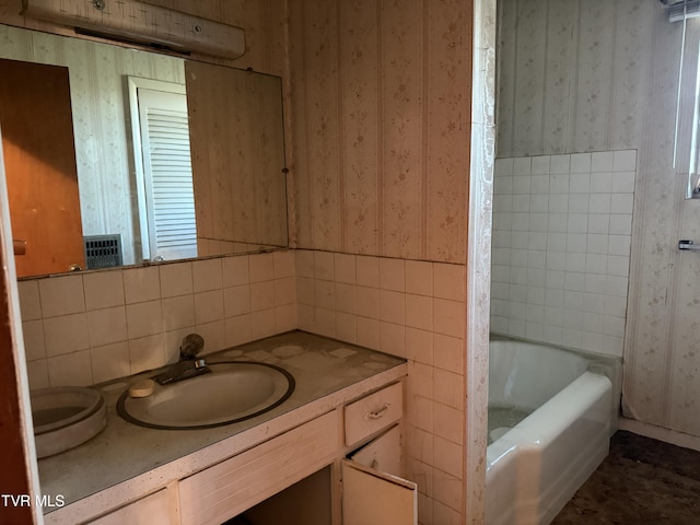 bathroom featuring a tub to relax in, tile walls, vanity, and wallpapered walls