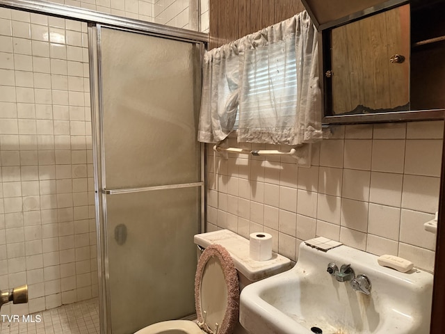 bathroom featuring tile walls, decorative backsplash, toilet, a shower stall, and a sink