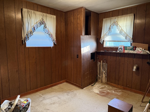 interior space with light floors, wood walls, and baseboards