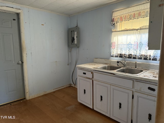 kitchen featuring light countertops, light wood-style floors, white cabinetry, a sink, and electric panel