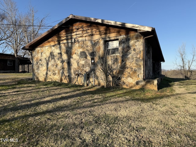 view of side of home with stone siding and a lawn