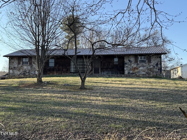 view of front of home with stone siding, a front lawn, metal roof, and a standing seam roof