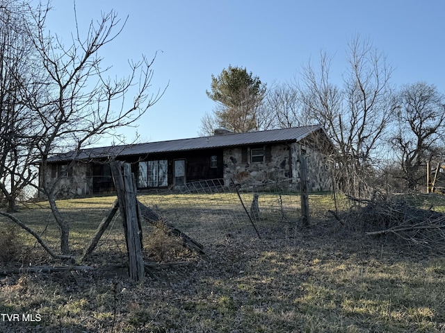 exterior space with metal roof, stone siding, and a chimney