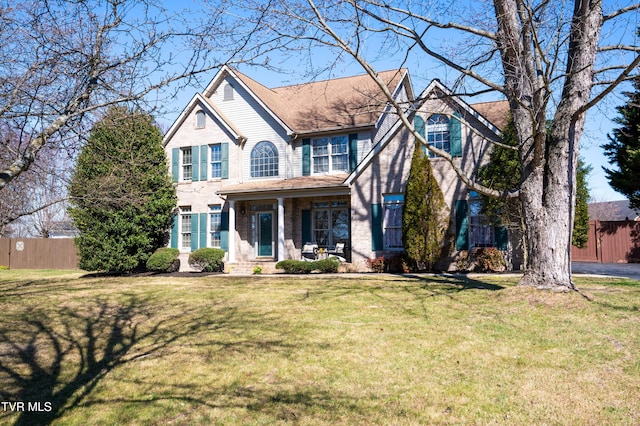 traditional home with brick siding, fence, and a front lawn