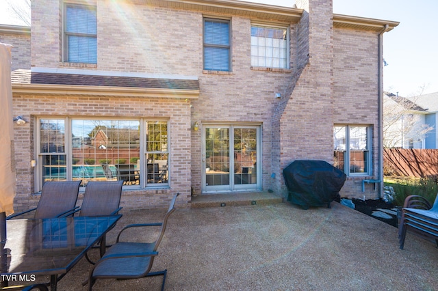 rear view of house with brick siding, fence, and a patio