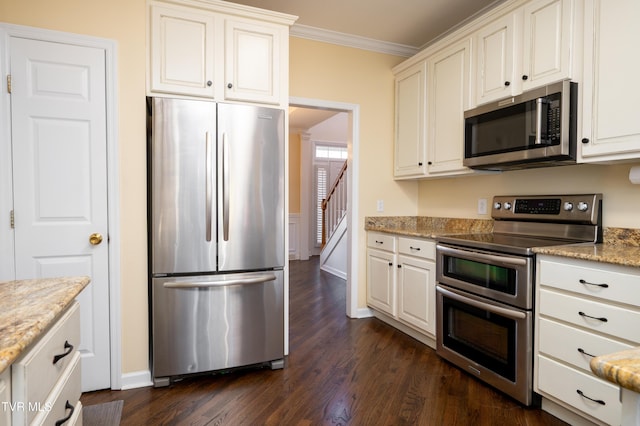 kitchen featuring dark wood-style flooring, appliances with stainless steel finishes, ornamental molding, white cabinetry, and light stone countertops