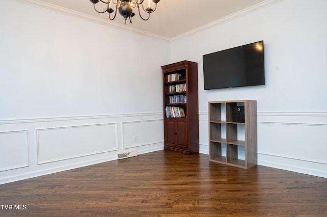 unfurnished living room featuring visible vents, a wainscoted wall, ornamental molding, wood finished floors, and an inviting chandelier