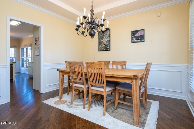 dining room featuring a notable chandelier, a wainscoted wall, dark wood-style flooring, a tray ceiling, and crown molding