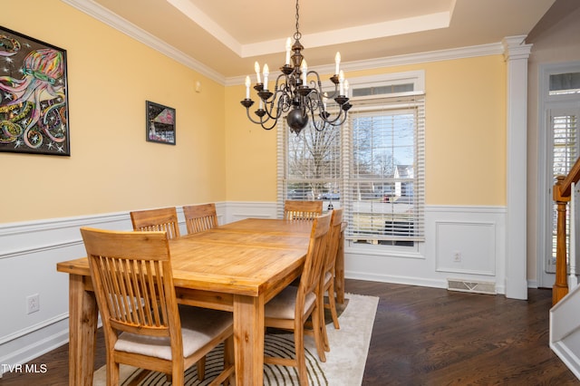 dining room with decorative columns, a tray ceiling, dark wood-style flooring, and a wealth of natural light