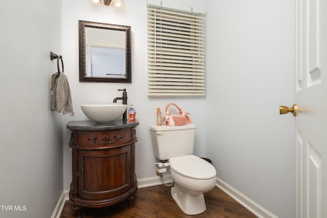 half bath featuring toilet, baseboards, wood finished floors, and vanity