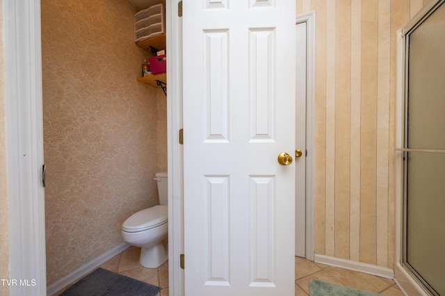 full bathroom with a shower with door, a closet, wallpapered walls, toilet, and tile patterned floors