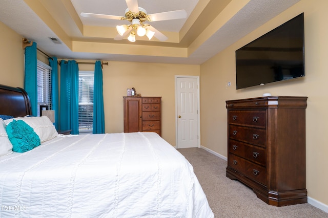 carpeted bedroom with visible vents, a tray ceiling, a ceiling fan, and baseboards