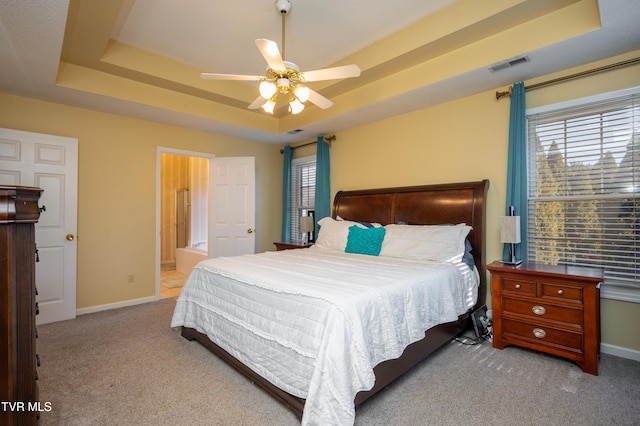 carpeted bedroom with baseboards, visible vents, and a raised ceiling