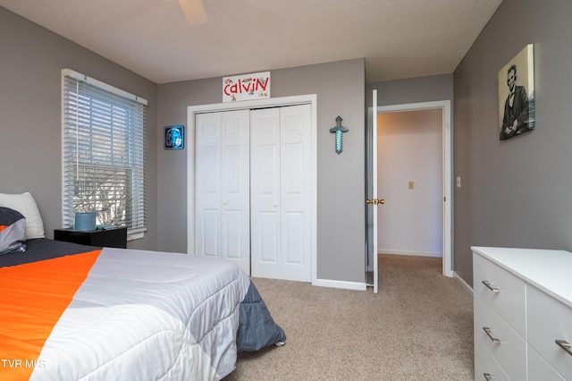 bedroom with a ceiling fan, a closet, light carpet, and baseboards