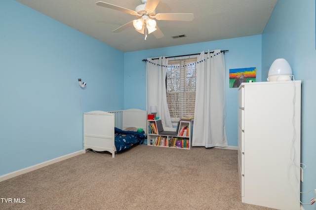 carpeted bedroom featuring a textured ceiling, ceiling fan, visible vents, and baseboards