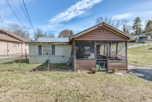 view of front facade featuring metal roof, fence, a front lawn, and a sunroom