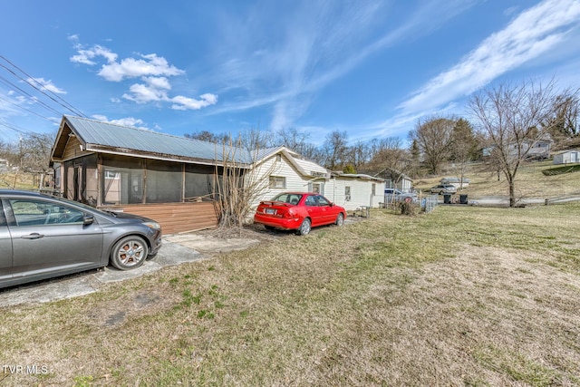 view of side of property featuring metal roof and a lawn