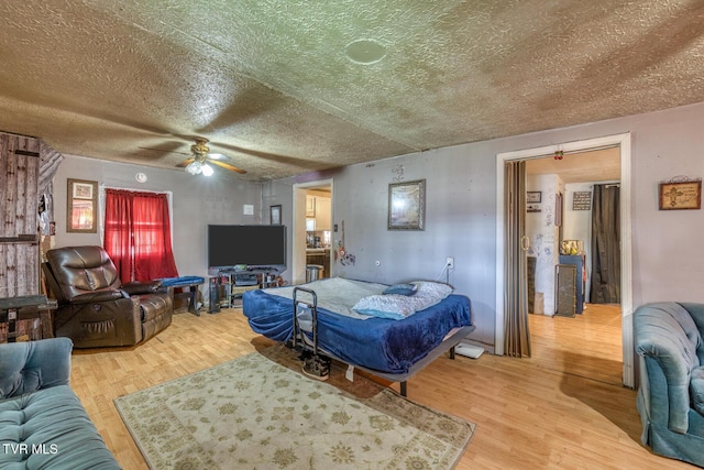 living area with light wood-style flooring, a ceiling fan, and a textured ceiling