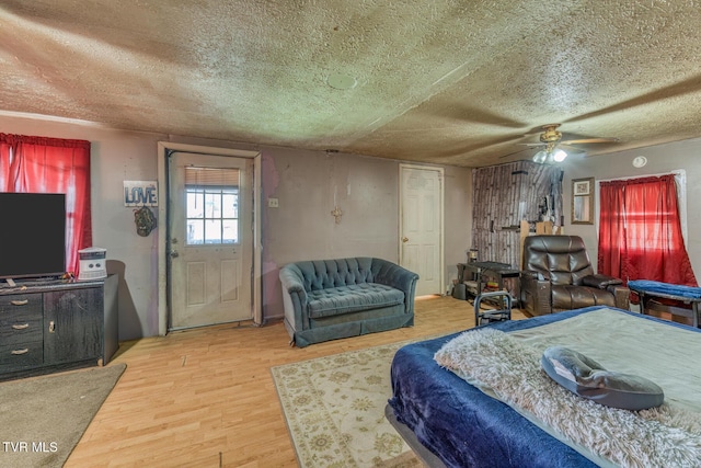 bedroom featuring a textured ceiling, ceiling fan, and light wood-style flooring