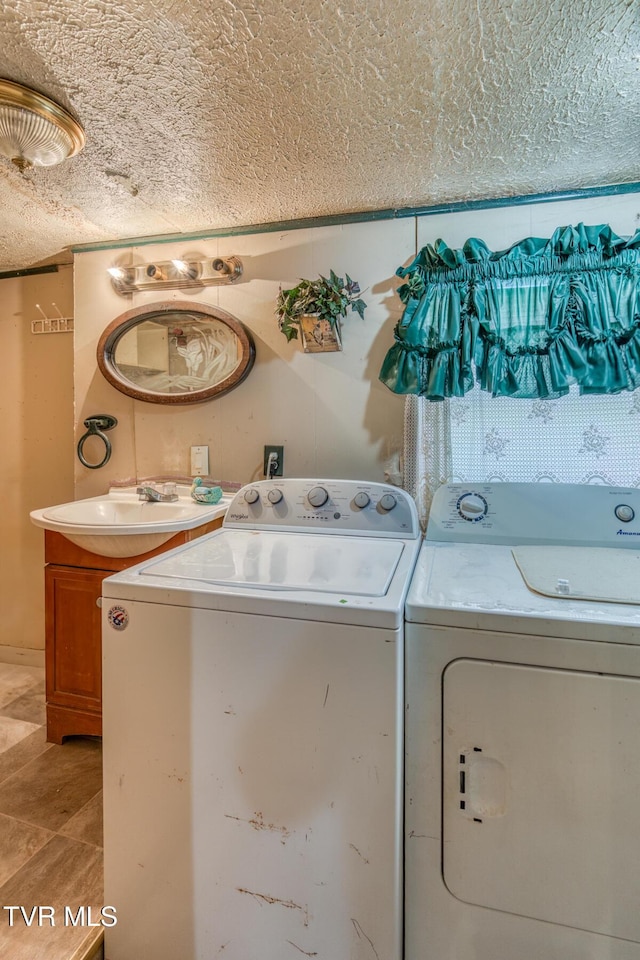 laundry area with washer and dryer, laundry area, a sink, and a textured ceiling