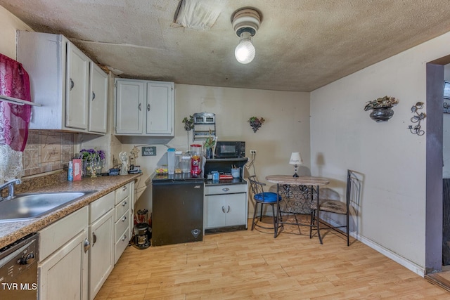 kitchen with black microwave, light wood-style floors, a sink, and dishwasher