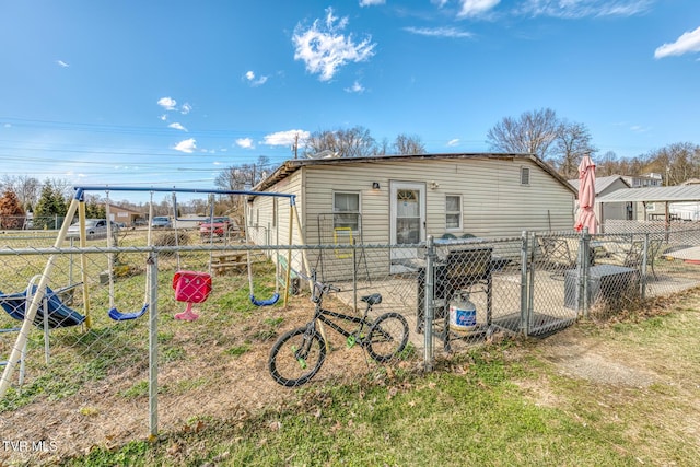 back of property with a gate, a playground, and fence