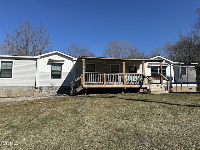 manufactured / mobile home with crawl space, a trampoline, and a front lawn