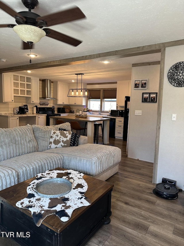 living area featuring dark wood finished floors, a textured ceiling, and ceiling fan