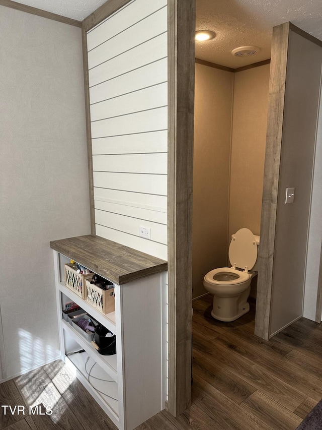 bathroom with visible vents, a textured ceiling, toilet, and wood finished floors