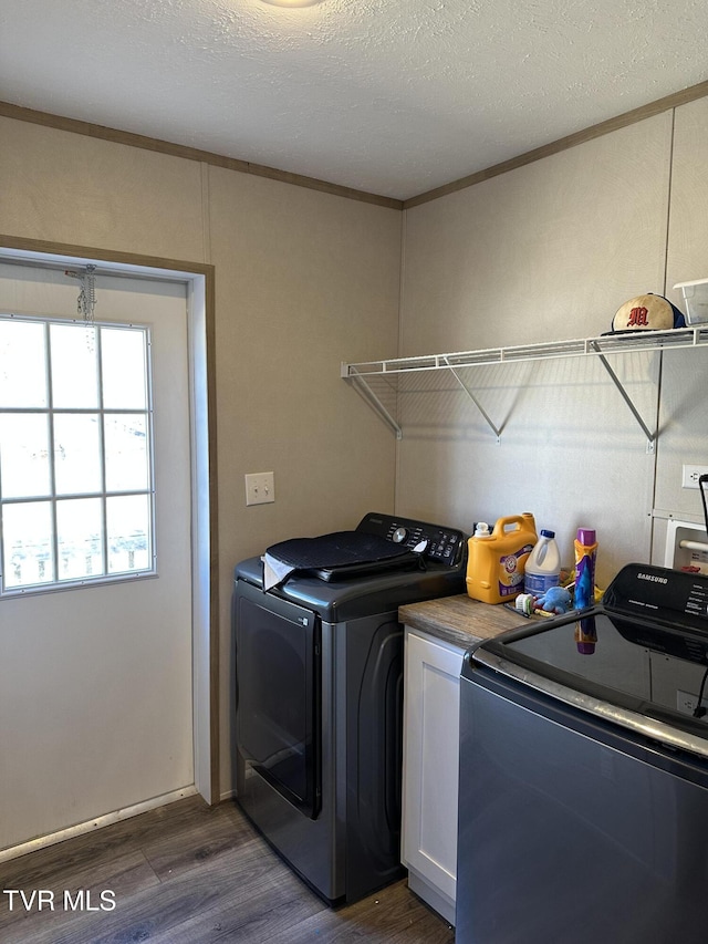 laundry area with washing machine and dryer, cabinet space, dark wood finished floors, and a textured ceiling