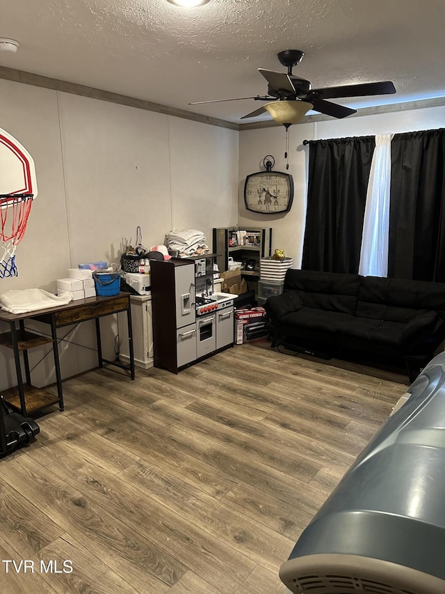 living room featuring ceiling fan, a textured ceiling, and wood finished floors