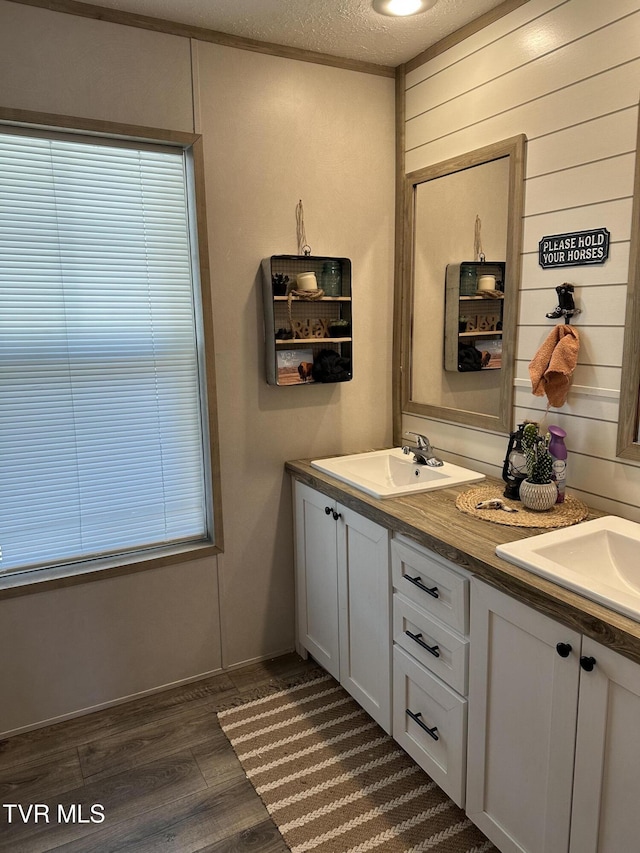 bathroom with double vanity, a sink, a textured ceiling, and wood finished floors