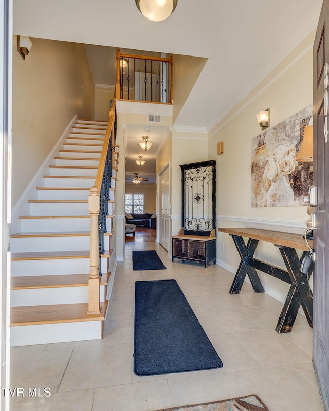 entrance foyer featuring ornamental molding, tile patterned floors, visible vents, and stairs