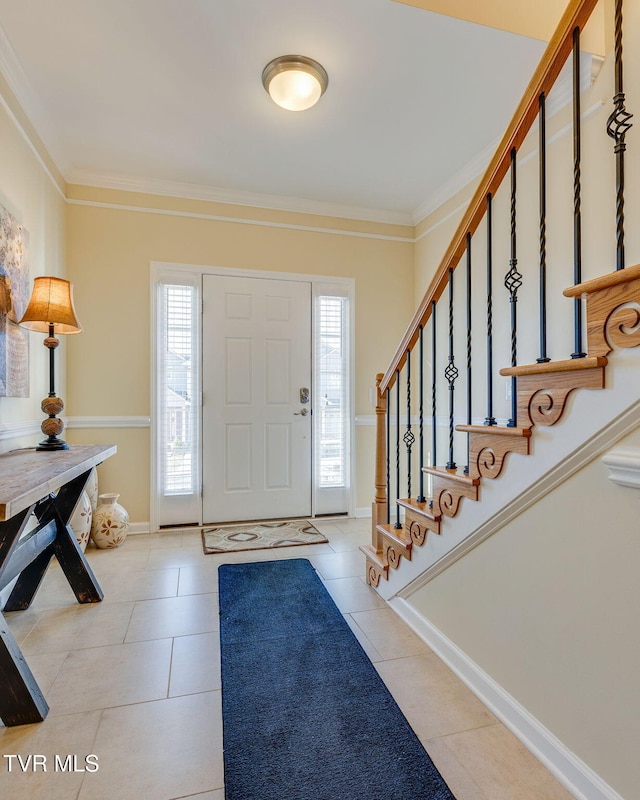 foyer with a healthy amount of sunlight, light tile patterned floors, stairs, and ornamental molding