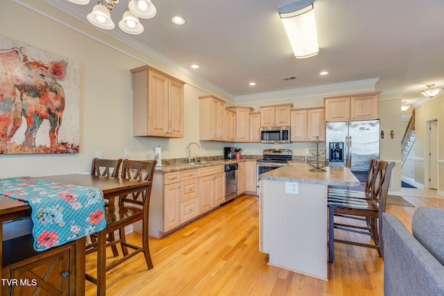 kitchen featuring appliances with stainless steel finishes, light wood-type flooring, light brown cabinets, and ornamental molding