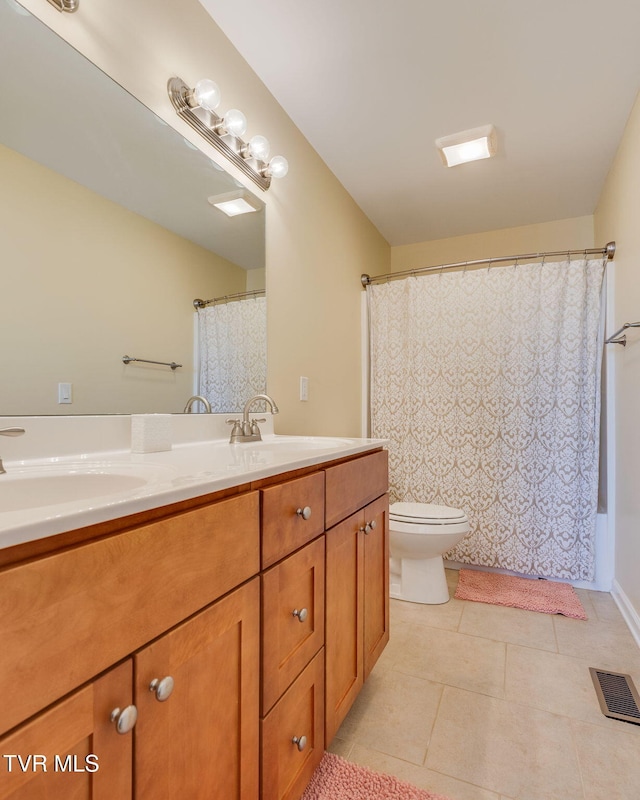 bathroom featuring double vanity, tile patterned flooring, a sink, and toilet