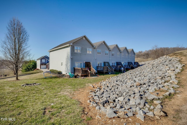 back of property with a yard, a deck, and an outdoor structure