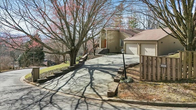 view of side of property with driveway, an attached garage, fence, and stucco siding