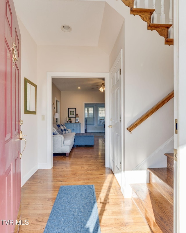 hallway featuring stairway, light wood-style flooring, and baseboards