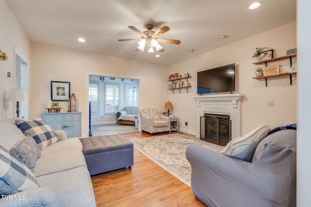 living area featuring recessed lighting, light wood-style floors, a fireplace, baseboards, and ceiling fan