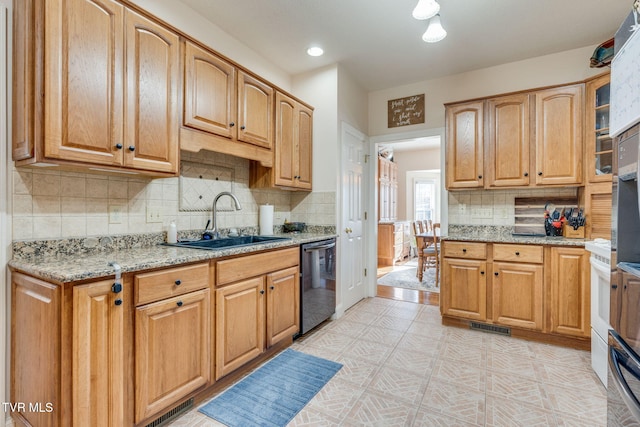 kitchen featuring light floors, black dishwasher, light stone counters, decorative backsplash, and a sink